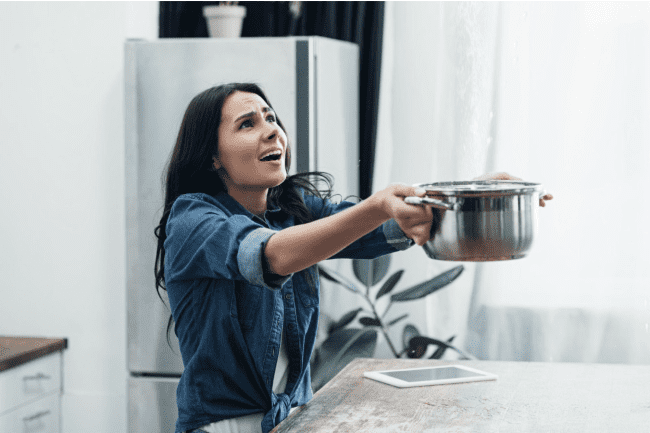woman catching water leak using pot woman catching water leak using pot