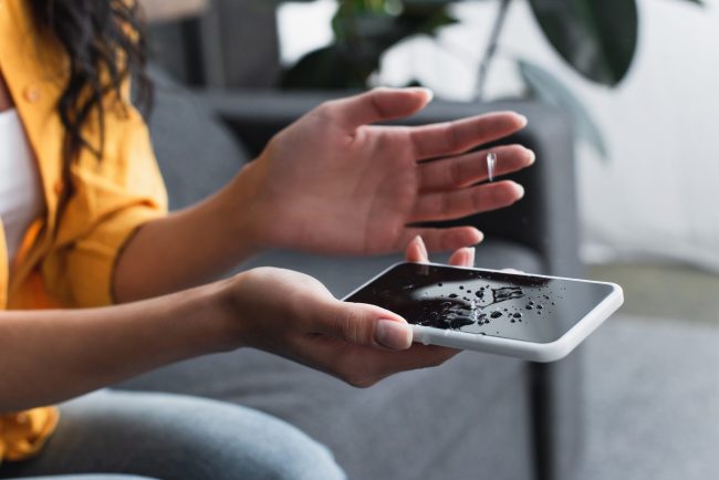 Partial view of woman holding water damaged smartphone water damage