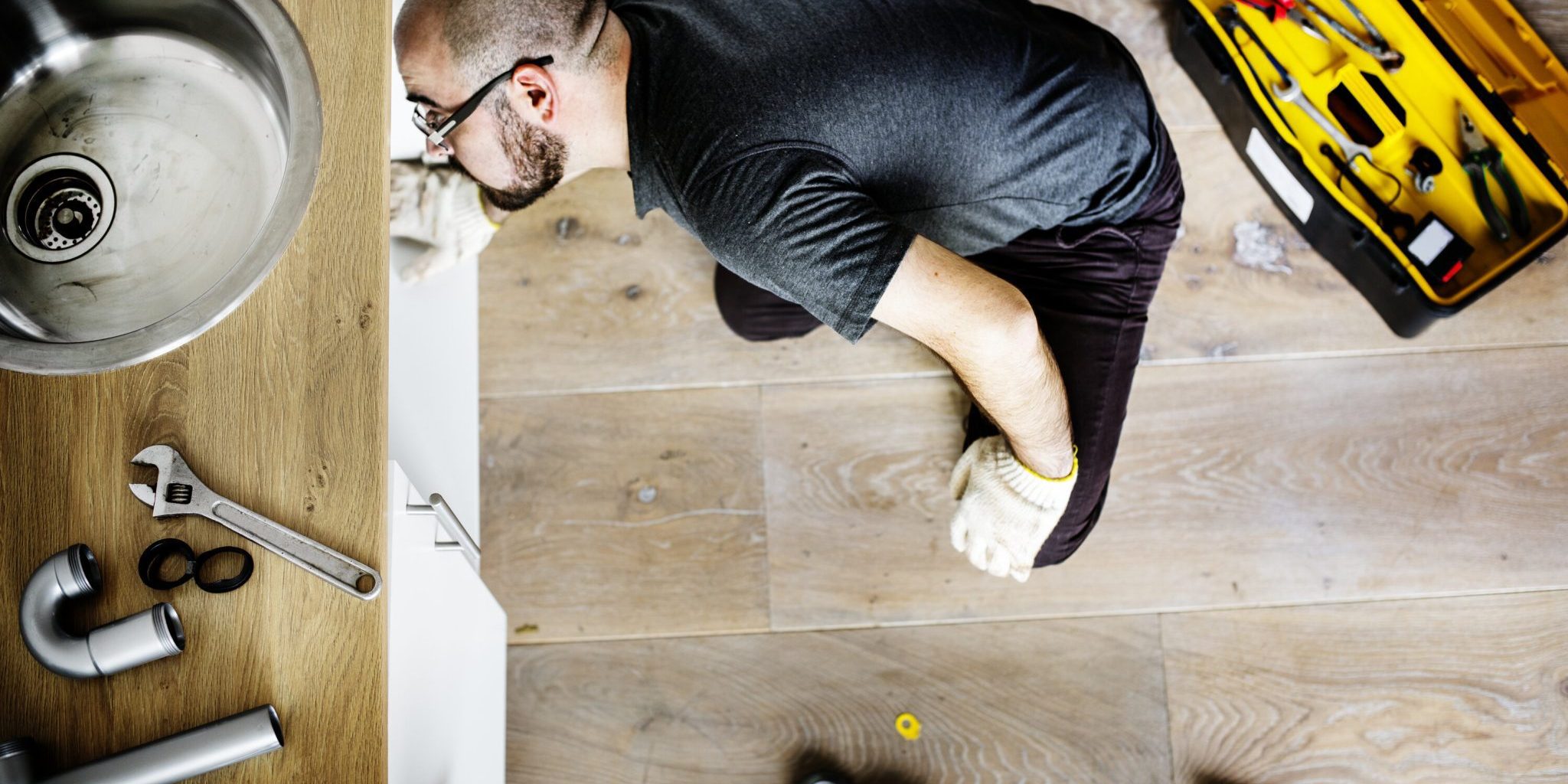Man fixing kitchen sink plumbing