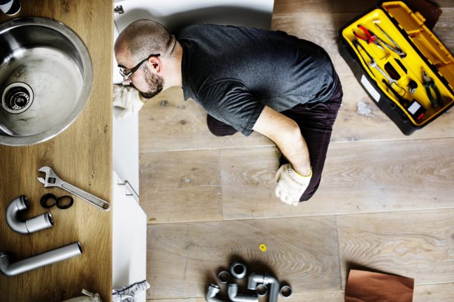 Man fixing kitchen sink plumbing